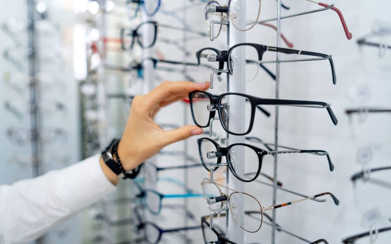 hand choosing pair of eyeglasses from display